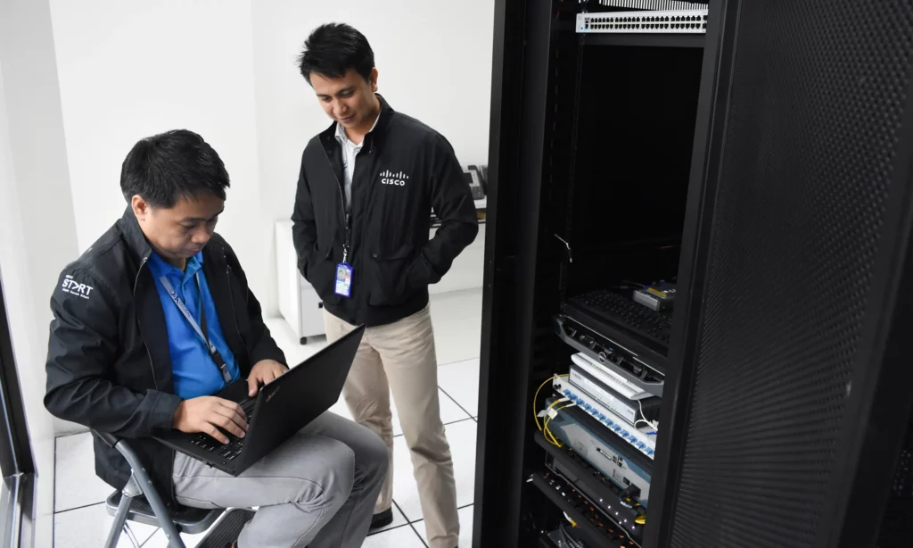 benefits of outsourcing 2 male DBA IT managers in the server room checking the current capacity and performance